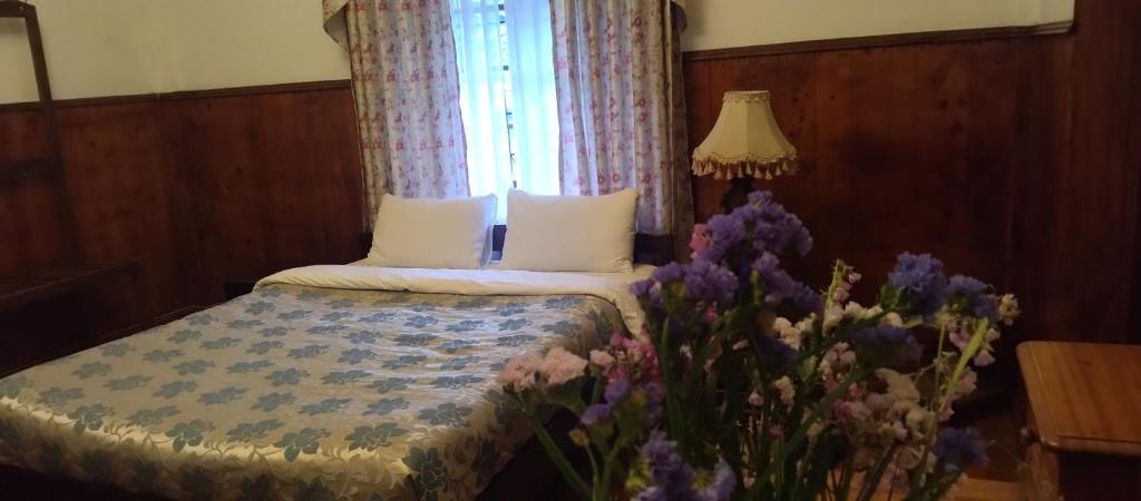 努沃勒埃利耶特列文酒店的一间卧室配有一张带窗户和紫色鲜花的床