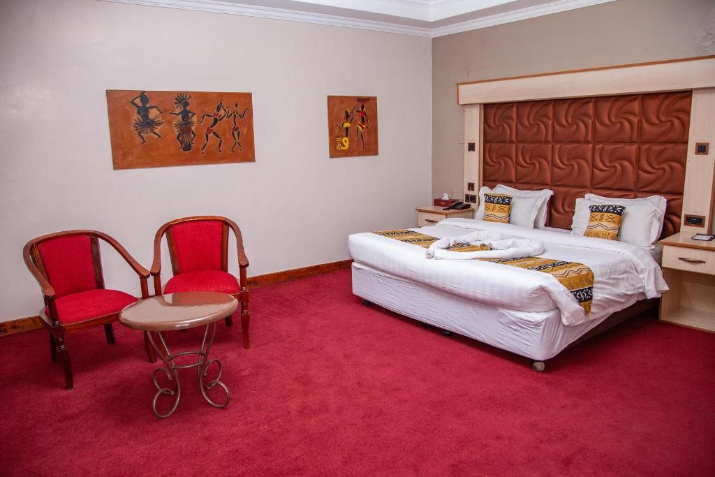 ThikaThe Luke Hotel Cravers Thika的一间卧室配有一张大床和两张红色椅子