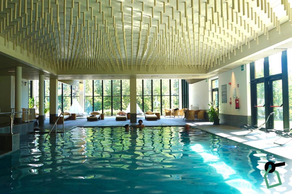 摩德纳迪-坎皮格里奥HOTIDAY Residence Campiglio的酒店大堂设有一座带大型天花板的游泳池