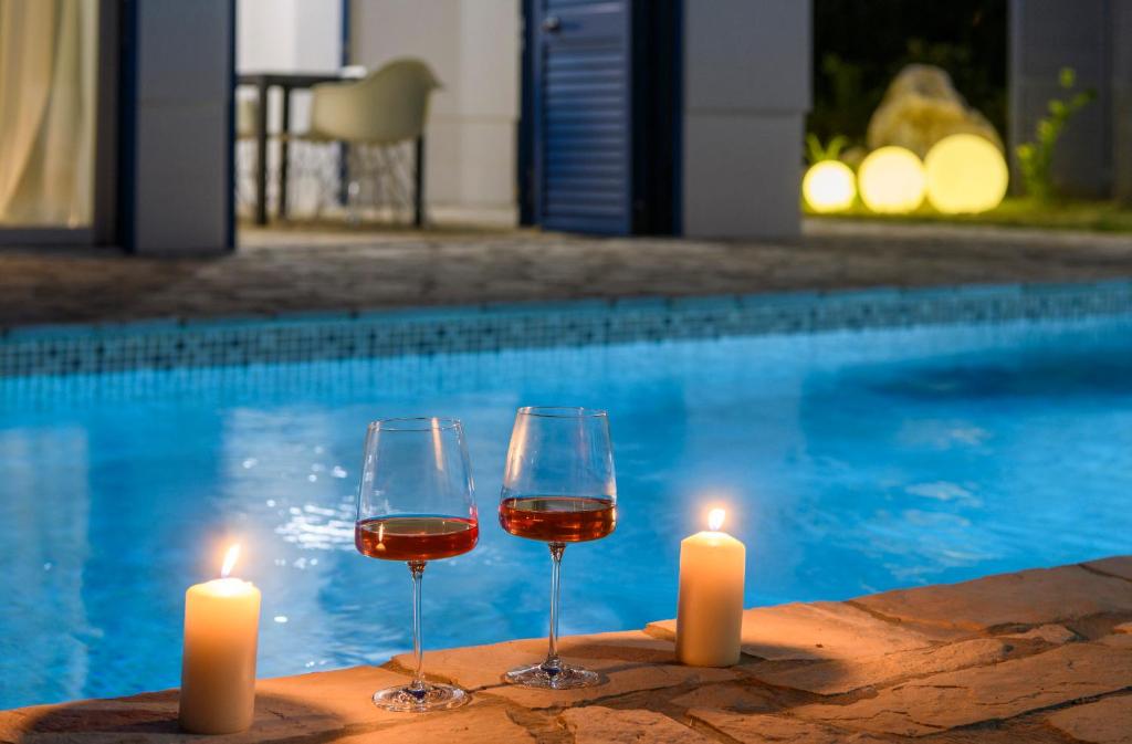 泽斯特拉格Holiday home Blue Sky的游泳池畔的两杯葡萄酒和蜡烛