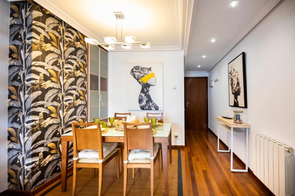 希洪Atico Martina Centro的用餐室配有桌椅和壁画