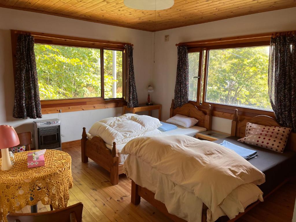 留寿都村太阳公公之家旅馆的一间卧室设有两张床、一张桌子和两个窗户。