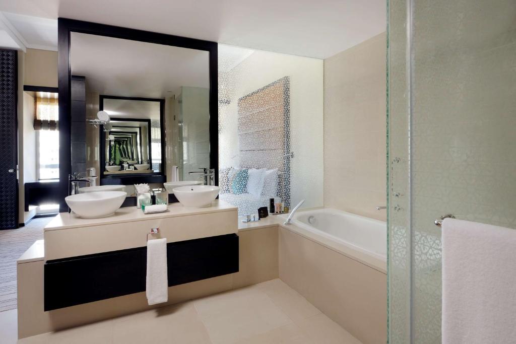 阿布扎比Southern Sun Abu Dhabi的浴室设有2个水槽、浴缸和镜子