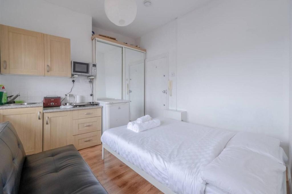 伦敦Bright & Quaint Studio Flat - Hornsey!的一间带白色床的卧室和一间厨房