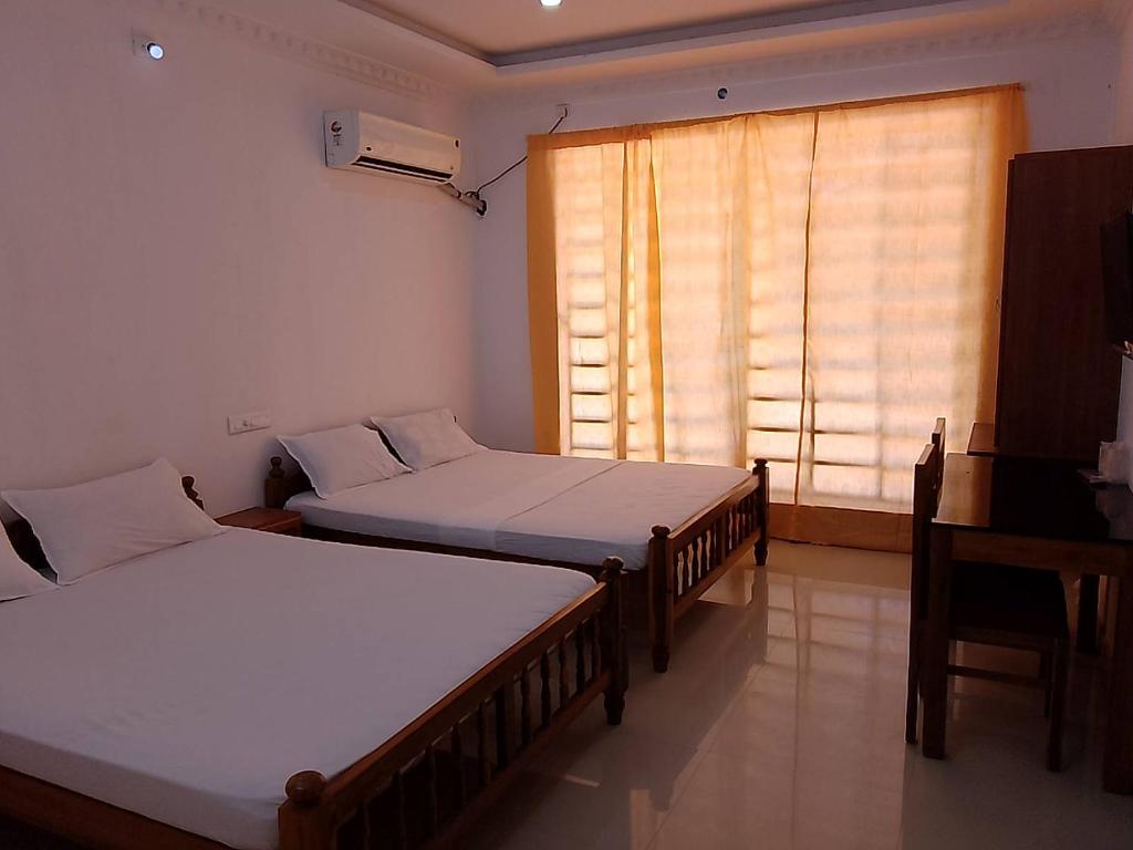可瓦兰Somatheertham Panchakarma Resort的带窗户的客房内的两张床