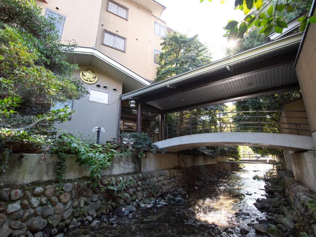 笛吹市Tabist Sakura no Yakata Hotel的一座建筑物前的溪流上的桥梁