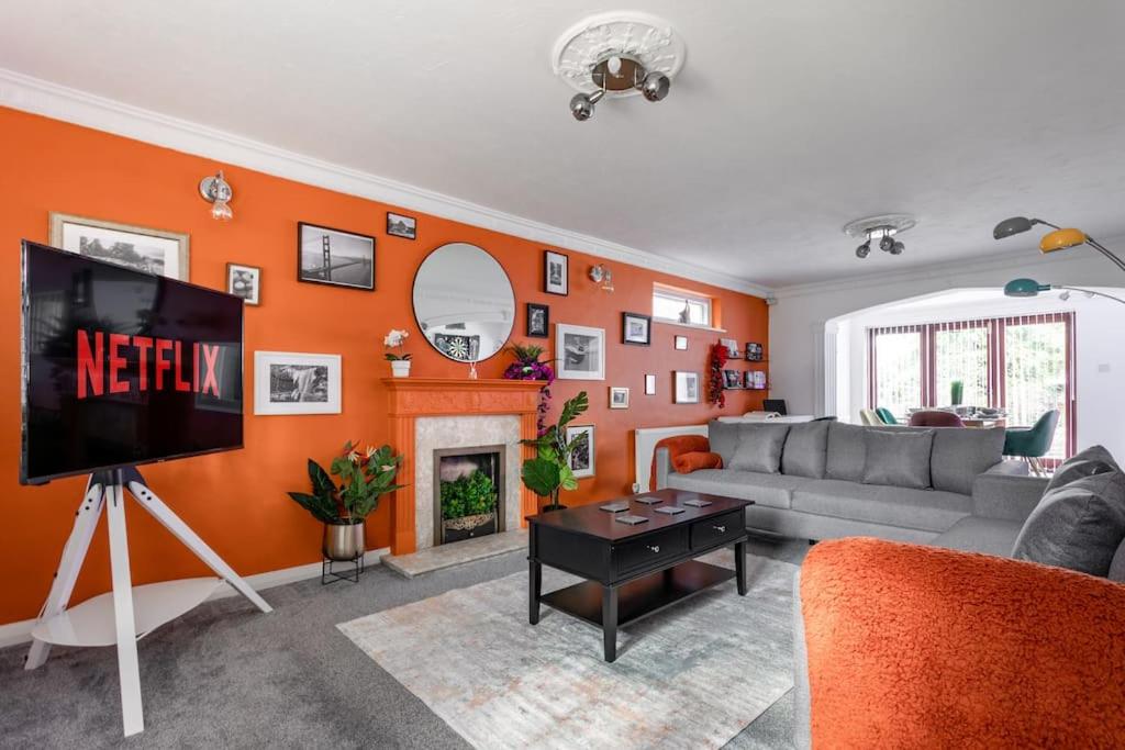 The Orange House Langdon Hills的客厅设有带电视的橙色墙壁