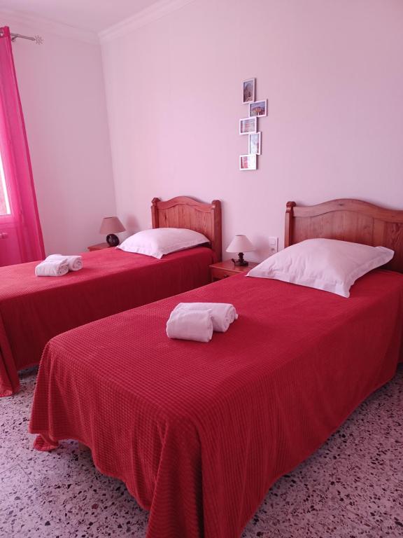 加尔加斯Gîte La Charité à proximité de Roussillon, Gordes的配有红色床单和白色枕头的客房内的两张床