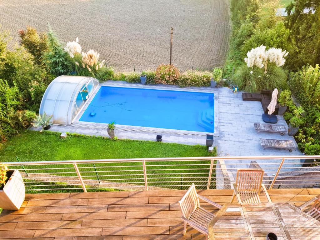 林茨Mountains and Lakes - Villa Gaumberg的庭院内的游泳池,配有两把椅子和一张桌子