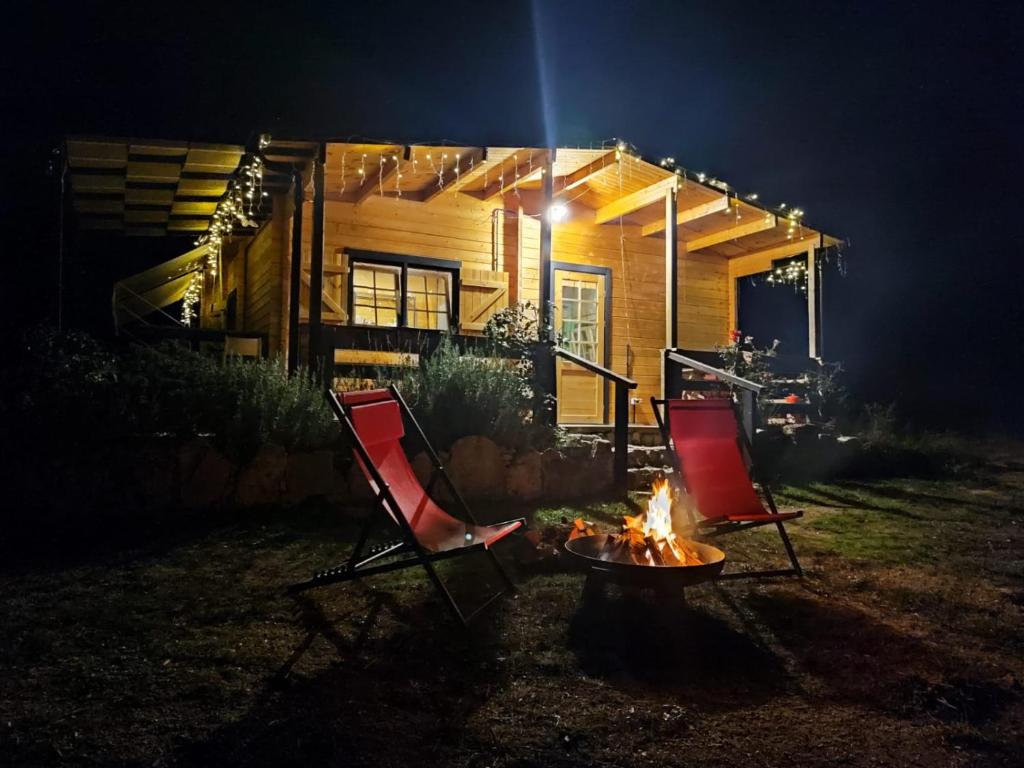 CalangianusEco Lodge nella natura "La Grande Quercia"的夜间房子前面有两把椅子和火