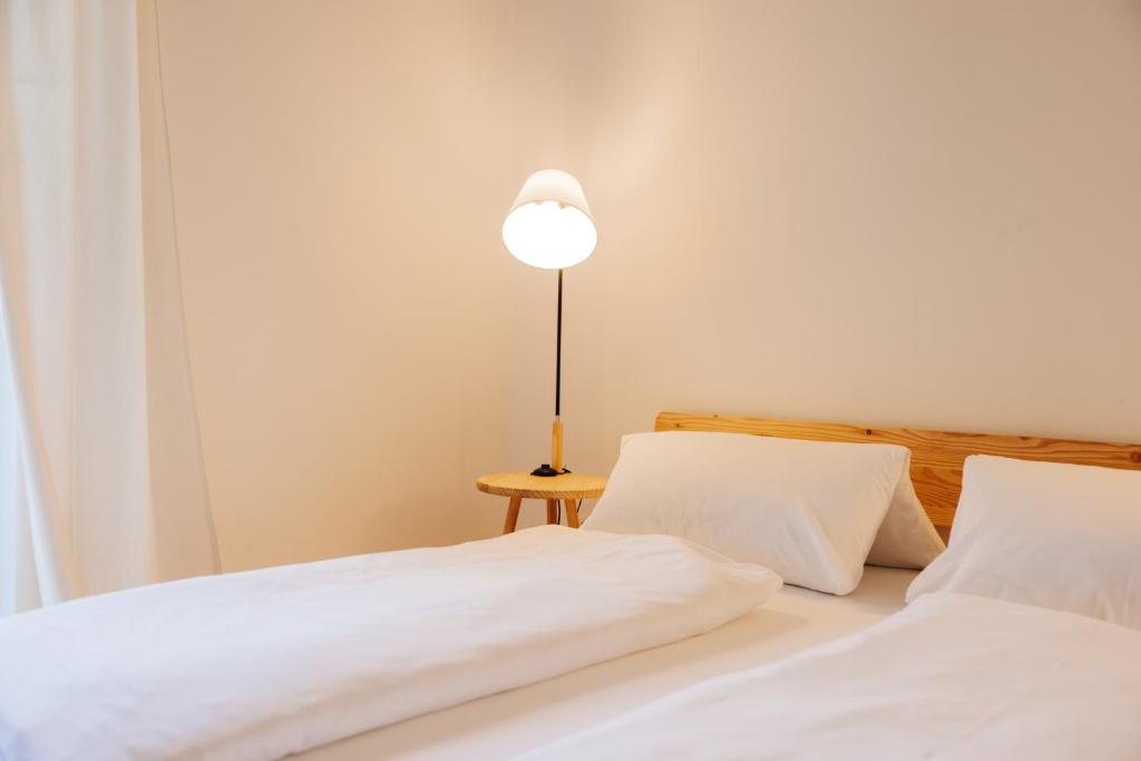 上德劳堡Boutiquehotel Lindenhof的两张带白色床单和台灯的床