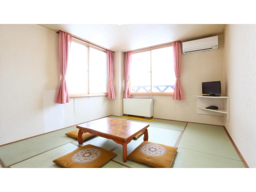 饭山市Hotel Silk in Madarao - Vacation STAY 79656v的客厅配有桌子和2扇窗户