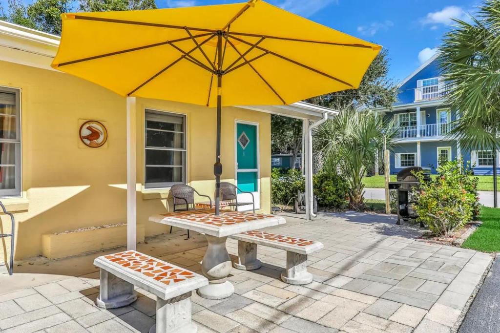 克利尔沃特Pelican Beach Studio #6的黄色的房子,配有野餐桌和雨伞