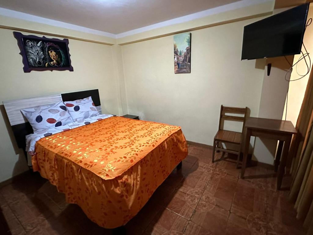 库斯科Hospedaje Qorichaska's的一间卧室配有一张床、一张桌子和一台电视