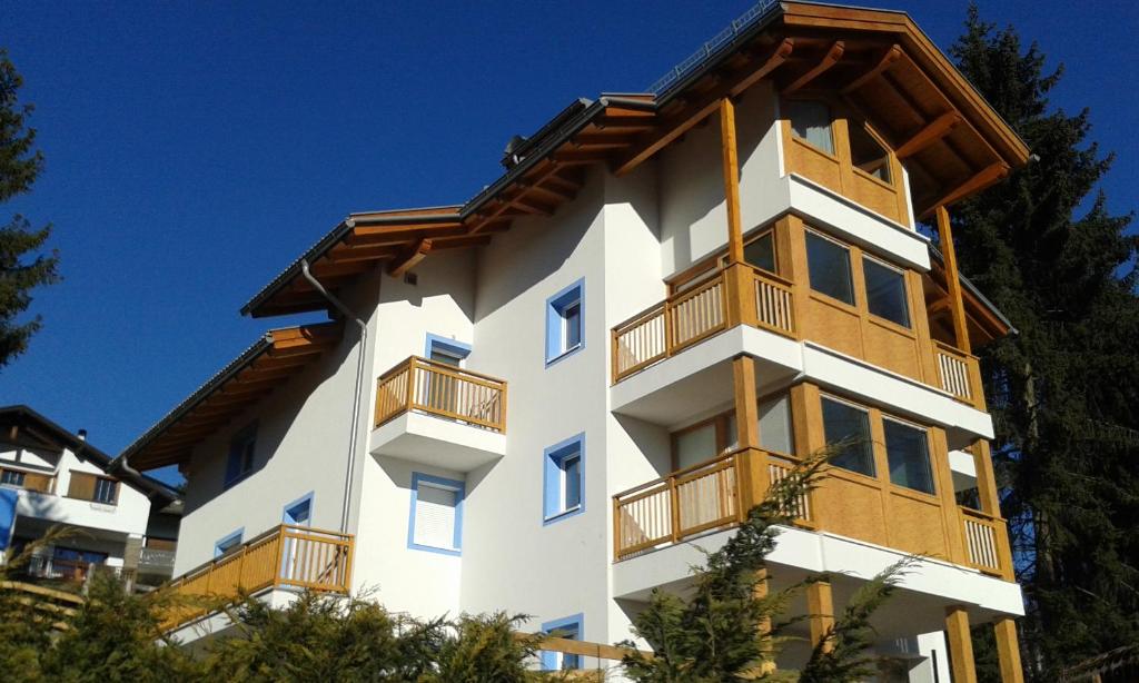 卡瓦莱塞Villa in Val di Fiemme的白色的建筑,设有木制阳台