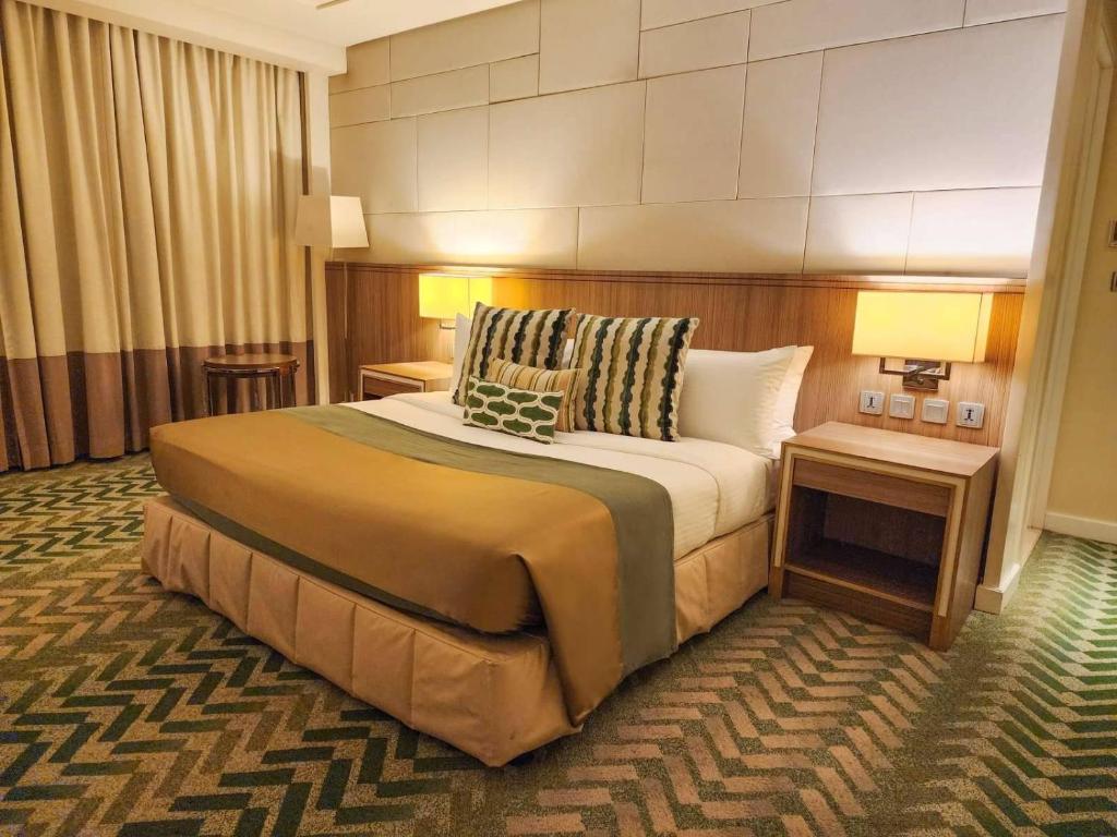 马尼拉百尼德梅森拉萨尔酒店的酒店客房带一张大床和两张桌子