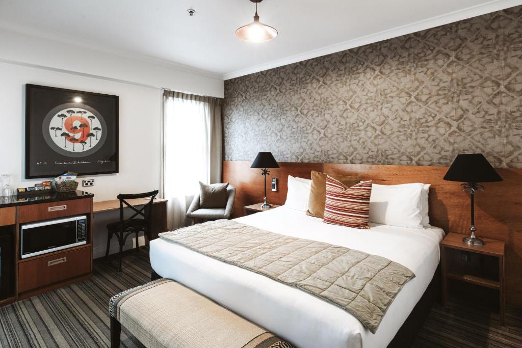 新普利茅斯斯塔特酒店的酒店客房带一张大床和一把椅子