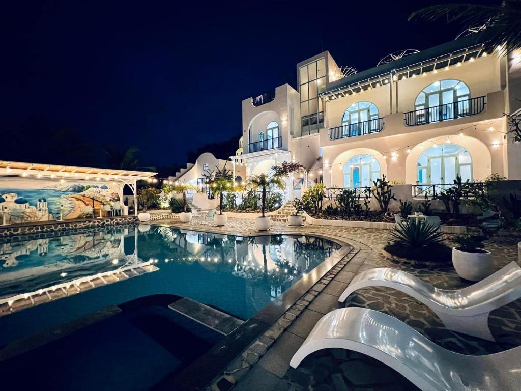 金兰Santorini Villa Cam Ranh的一座在晚上设有游泳池的大房子