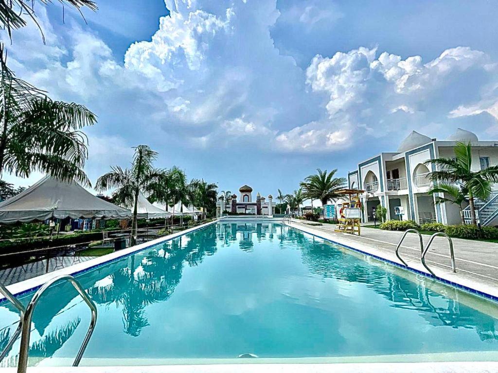 NaicTorres Farm Resort powered by Cocotel的拥有蓝水和棕榈树的度假村的游泳池