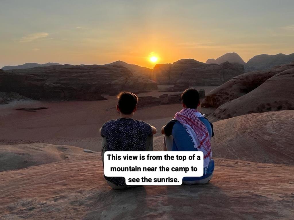 瓦迪拉姆Bedouin Tours Camp的两人坐在沙漠里,欣赏日落