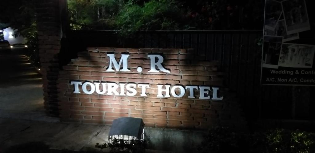 阿努拉德普勒MR Tourist Hotel的砖墙上的旅游酒店标志