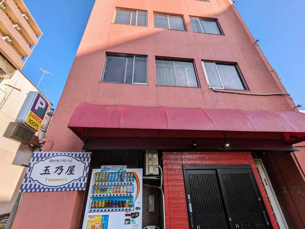 静冈駿府城下町の宿　玉乃屋的一座高大的红色建筑,前面有标志