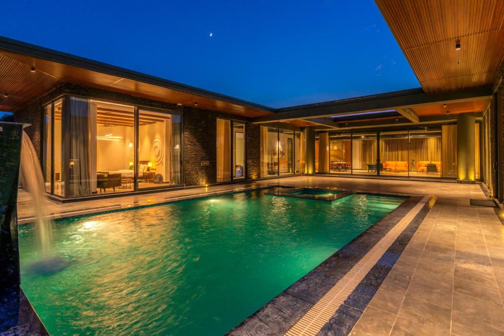 新德里StayVista's Anantam - Villa with Massive Outdoor Pool with Deck & Sprawling Lawn的房屋中间的游泳池