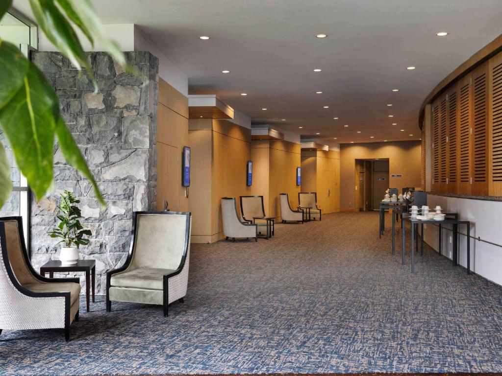 奥克兰奥克兰艾勒斯利诺富特酒店的一间设有椅子和石墙的等候室