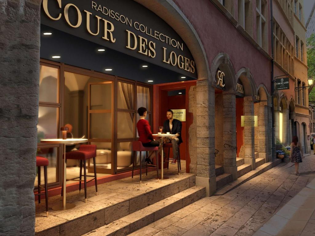 里昂Cour des Loges Lyon, A Radisson Collection Hotel的坐在商店外桌子上的一对夫妇