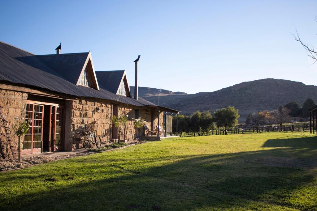 富里斯堡Moolmanshoek Private Game Reserve的一座石头房子,在田野旁边设有草地庭院