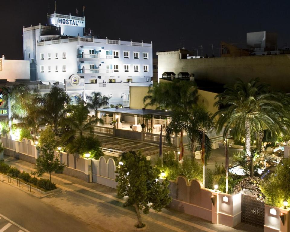 Beniparrell奇奎特之家酒店的一座白色的大建筑,有棕榈树和灯
