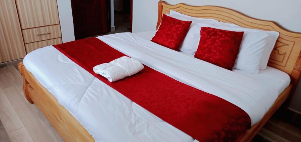 纳库鲁GOLDEN PALM 3的一张铺有红白床单和红色枕头的床