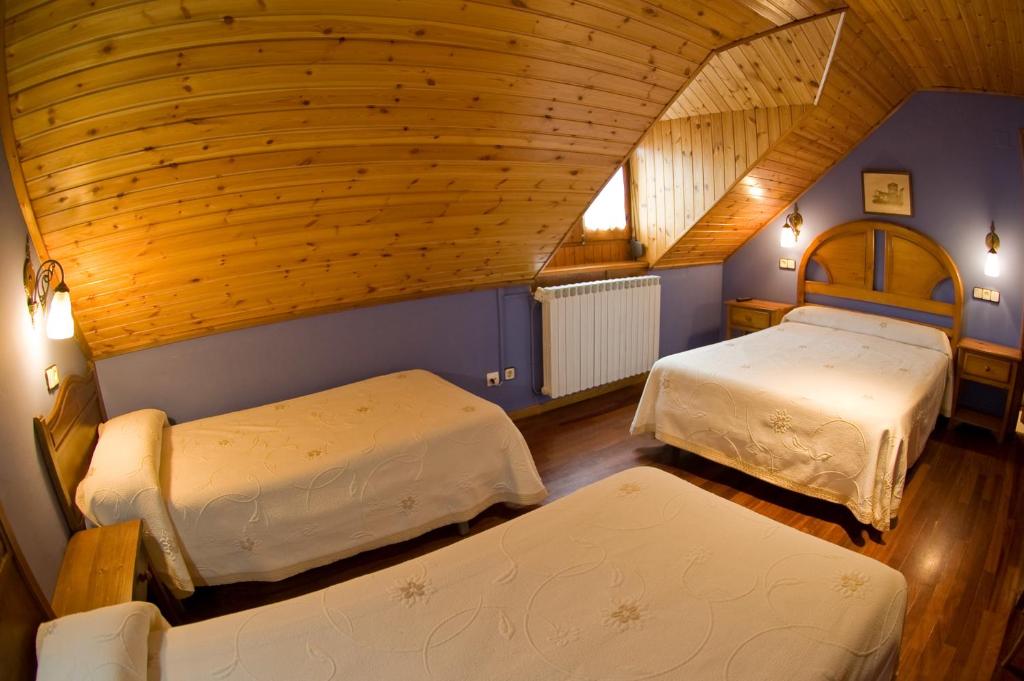 贝纳斯克Hotel Avenida Benasque的一间卧室设有两张床和木制天花板