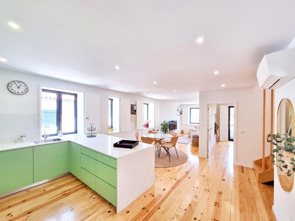 科维良Tílias House的一间厨房,配有白色和绿色的橱柜和一间用餐室