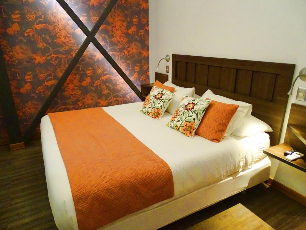 圣地亚哥BHB Hotel Boutique的一间卧室配有一张带橙色毯子和枕头的床