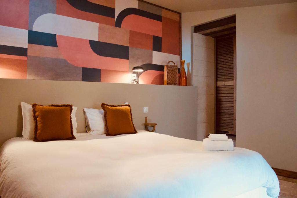 Saint-BauzélyMaison Guy的卧室配有带橙色枕头的大型白色床