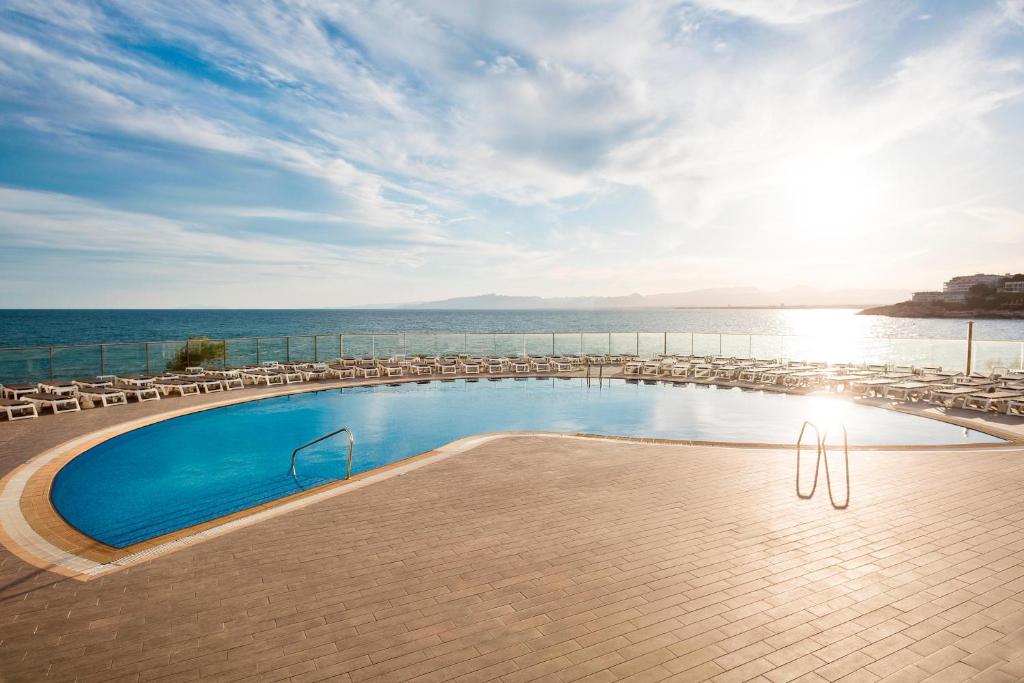 萨洛Hotel Best Negresco的一个带椅子的游泳池,背景是大海