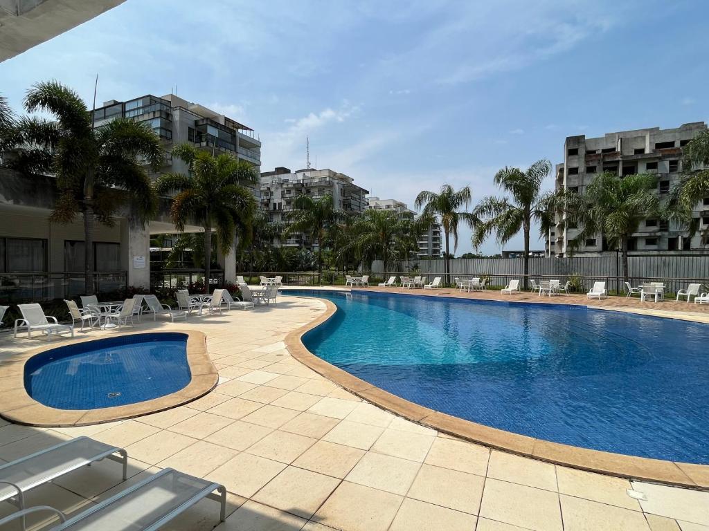 曼加拉蒂巴Apartamento Rio Marina Resort的一座带椅子和棕榈树的游泳池以及建筑
