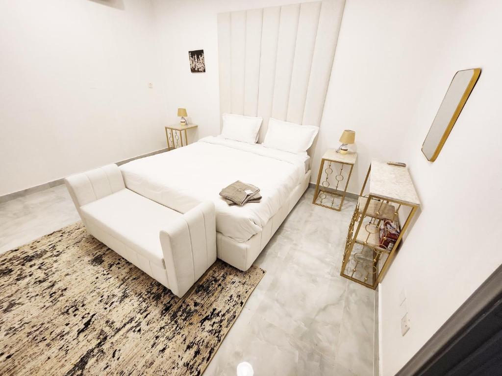 艾恩Moods Holiday Homes的白色的卧室配有白色的沙发和椅子