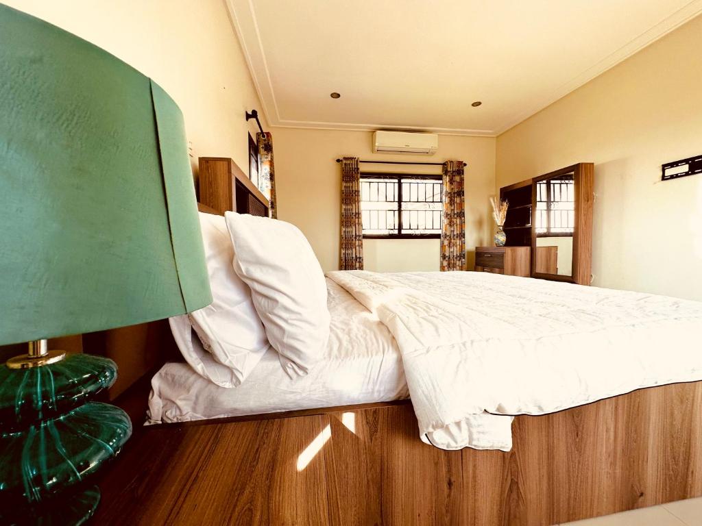 阿克拉Aspen Luxury Villa的一间卧室配有一张带白色床单的大床