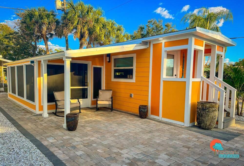 萨拉索塔Pinecraft Sunset Tiny Home的一座橙色的小房子,在庭院里配有电视