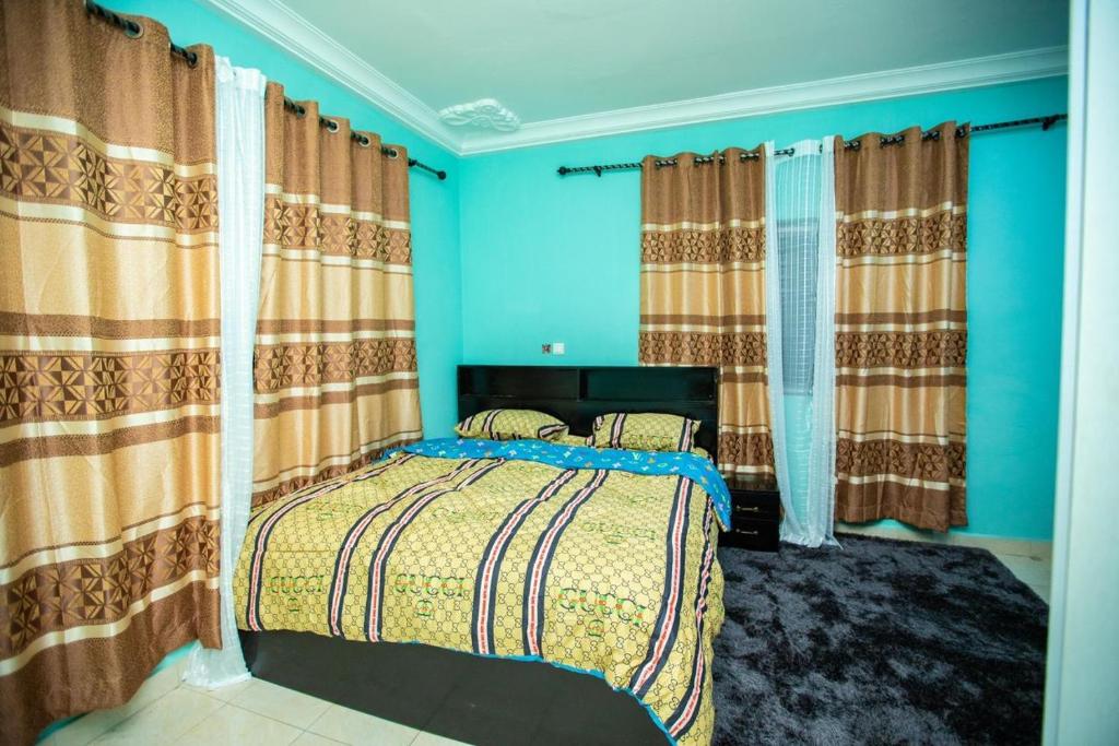 KasoaMatata Homes Airbnb的一间卧室配有一张带蓝色墙壁和窗帘的床