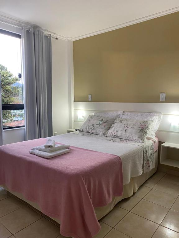 圣洛伦索Pousada da Mariinha的一间卧室配有一张带粉色毯子的大床