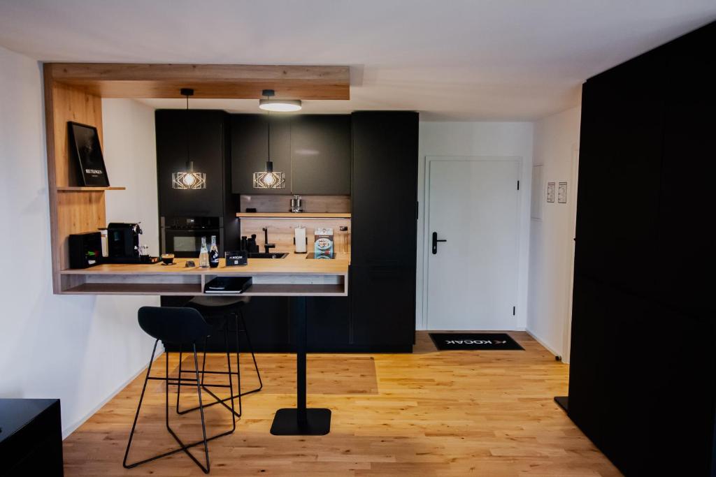 罗伊特林根KOCAK - Exklusives Apartment in Zentrumsnähe的一间厨房,配有黑色橱柜和一个带凳子的酒吧