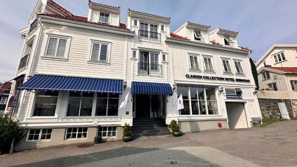 格里姆斯塔Clarion Collection Hotel Grimstad的白色的建筑,上面有蓝色的遮阳篷
