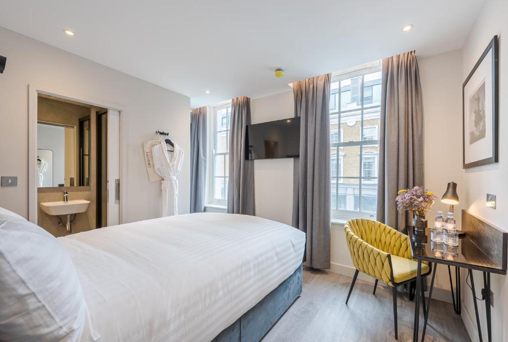 伦敦St Pancras Inn的酒店客房配有床、书桌和水槽