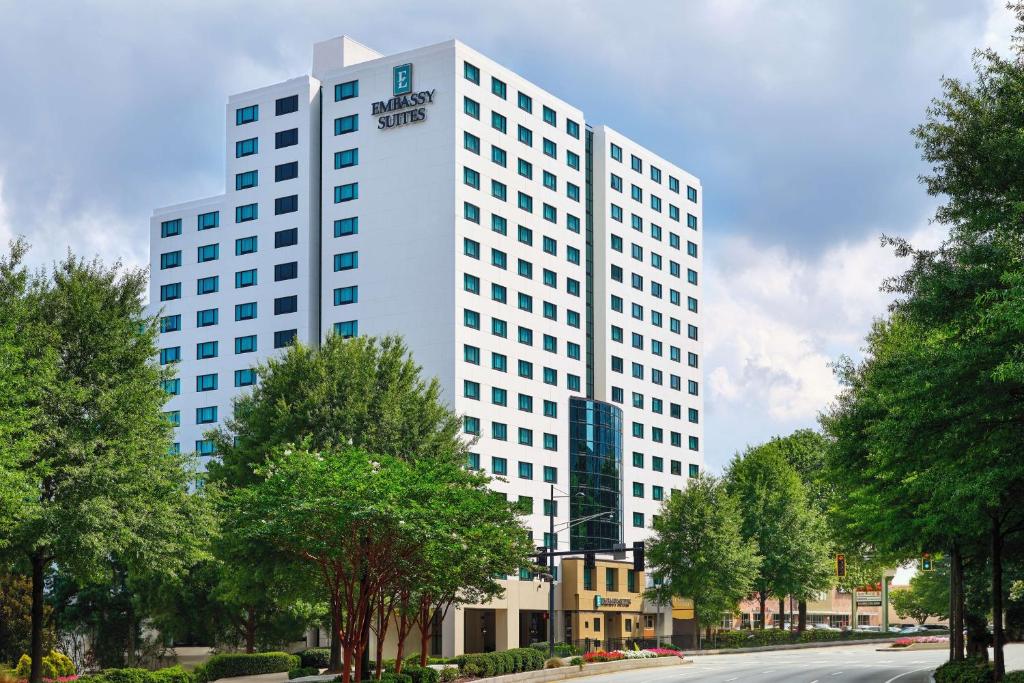 亚特兰大Embassy Suites by Hilton Atlanta Buckhead的一条高大的白色建筑,在街道前有树木