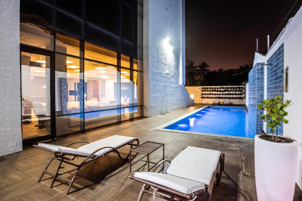 卡姆布库Hotel de Luxo Tango Suites & Coworking Cumbuco的一个带两把椅子的庭院和一个游泳池