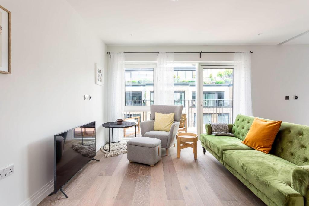伦敦Modern Chelsea Apartment的客厅配有绿色沙发和椅子