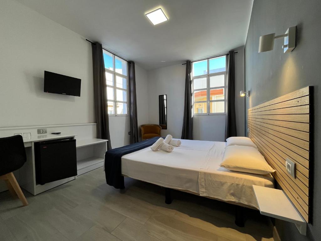 Buzanada卡桑德拉酒店的一间卧室配有一张床和一台电视,部分设有窗户。